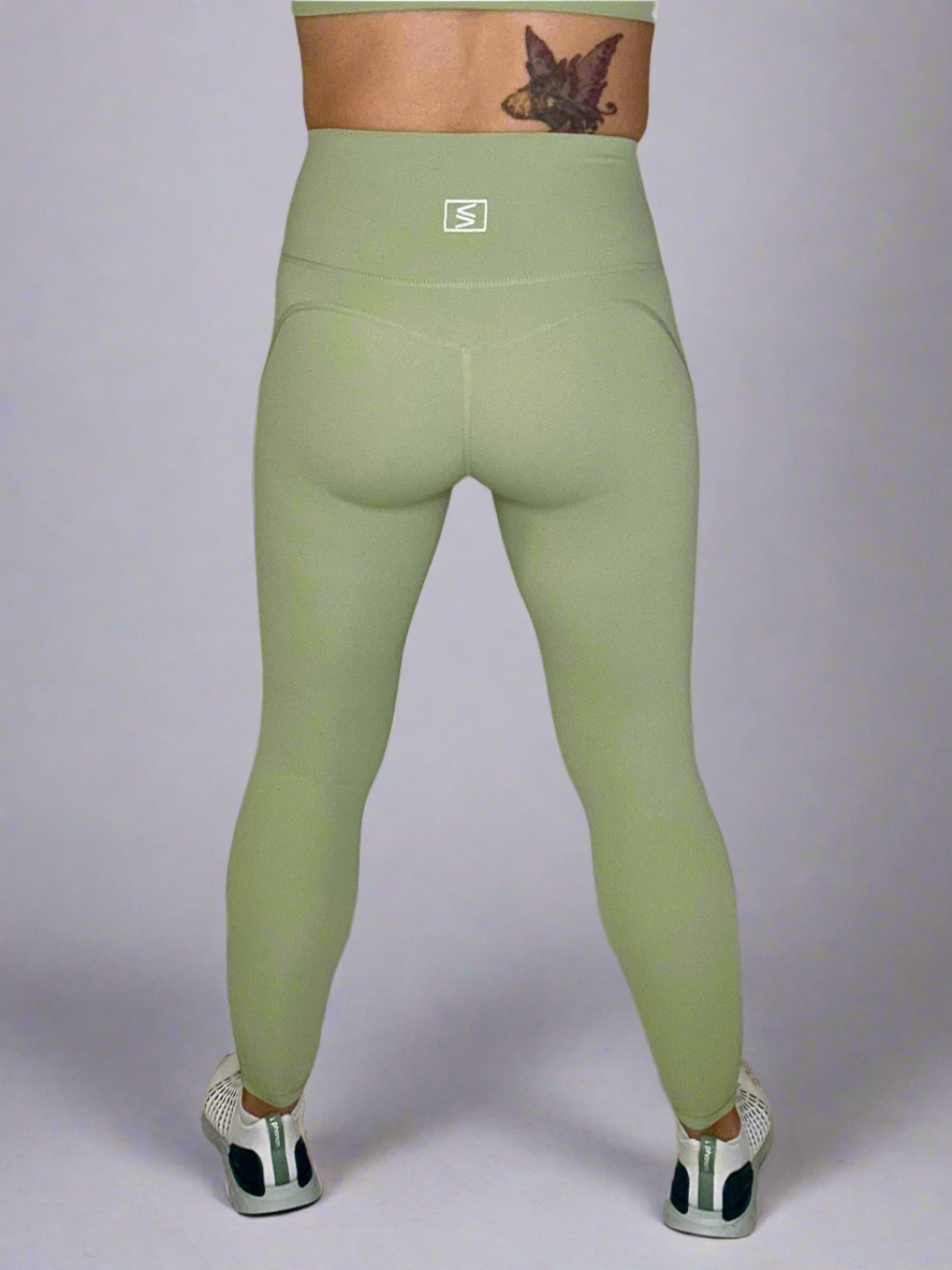 Backside of female model wearing Powerflow Leggings in Mint color.