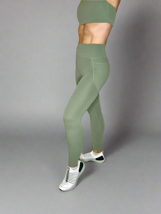 Model showcasing Rival Fit Gear Ignite Pocket Leggings in Moss side view.
