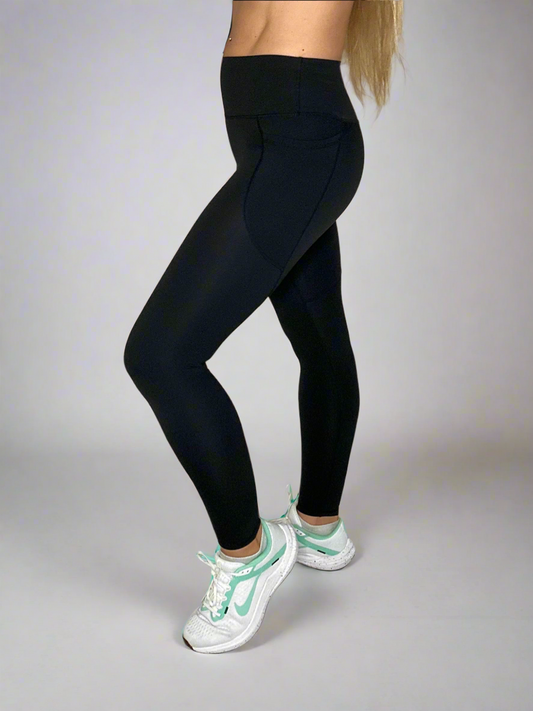 Model wearing Rival Fit Gear Ignite Pocket Leggings in Black in professional studio setting. 