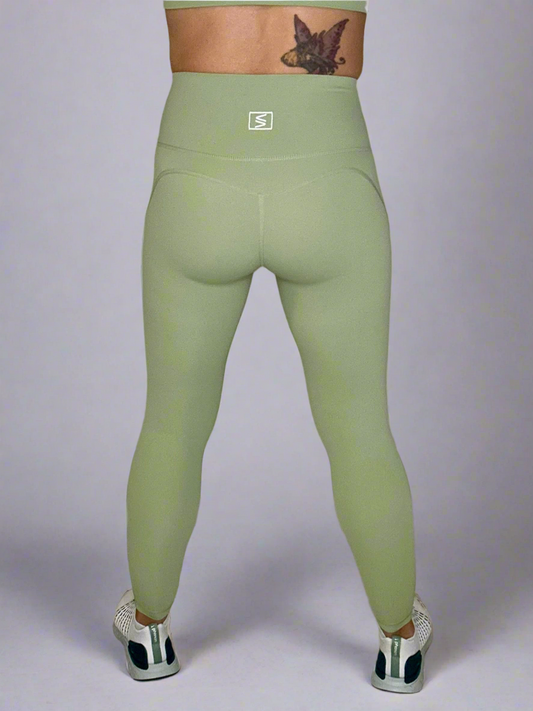 Backside of female model wearing Powerflow Leggings in Mint color.